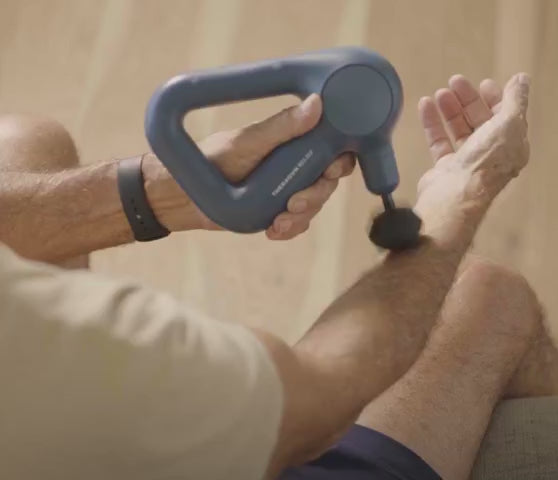 Theragun Relief massagegun in gebruik, close-up van de percussiebeweging